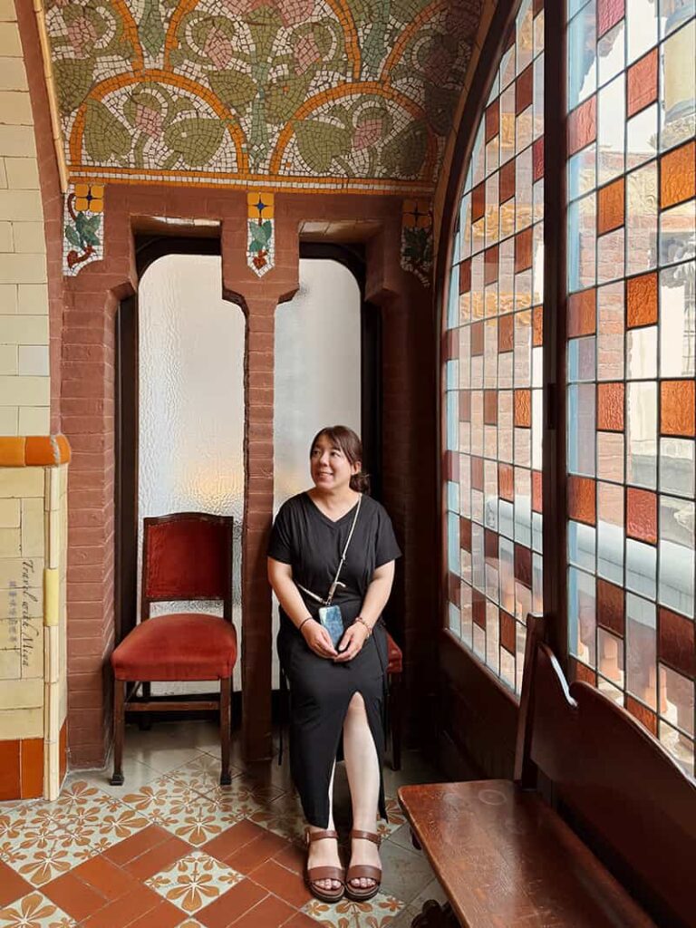 加泰隆尼亞音樂宮休息廳橘色方塊彩繪玻璃窗旁坐著休息