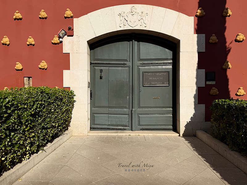 達利戲劇博物館土紅色外觀建築-綠色大門和牆上黃色凸凸的物體